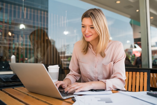 Portrait of young businesswoman working on her laptop at a coffee shop. Business concept.