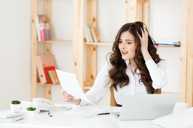 Portrait of Young Businesswoman working in her office with serious facial expression with document report.