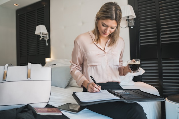 Portrait of young businesswoman working at the hotel room. Business travel concept.