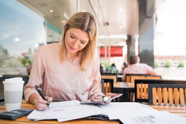 Portrait of young businesswoman working with a digital tablet at coffee shop. Business concept.