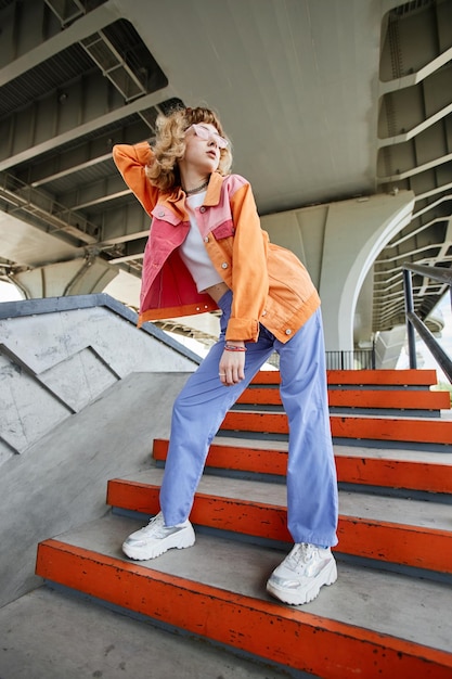 Portrait of young carefree woman wearing colorful street style outdoors in urban setting