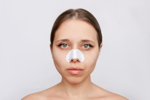 Portrait of young caucasian attractive woman with cleaning nose strips from blackheads or black dots