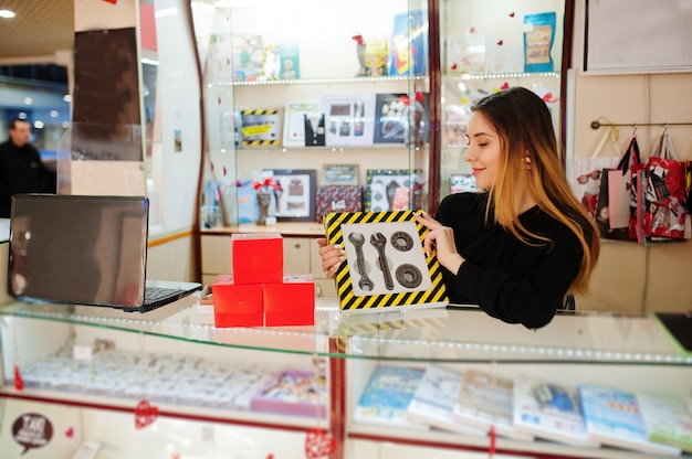 Portrait of young caucasian female woman seller hold set of mechanic tools made by chocolate. Small business of candy souvenirs shop. Present for real man.