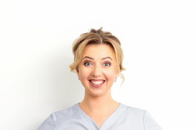 Ritratto di una giovane donna caucasica felice medico che indossa abiti da lavoro blu sorridente contro il bianco