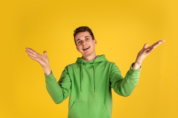 Portrait of young caucasian man isolated on yellow studio background