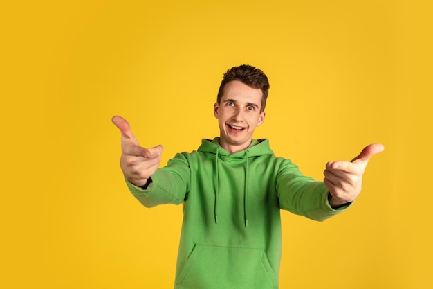 Portrait of young caucasian man isolated on yellow studio background