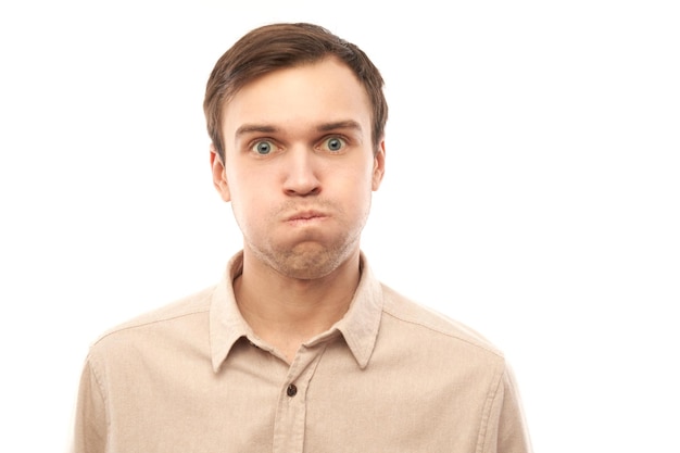 Portrait of young caucasian man puffing cheeks with funny face isolated on white studio background Humor concept mouth inflated with air crazy expression