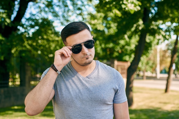 Portrait of a young caucasian man in sunglasses on the background of trees