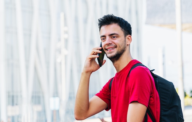 Ritratto di un giovane uomo caucasico che parla al telefono con lo sfondo fuori fuoco