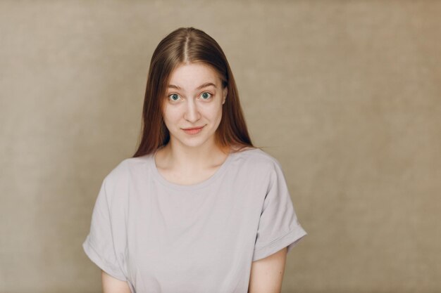 Portrait of young caucasian woman looking at camera against beige background