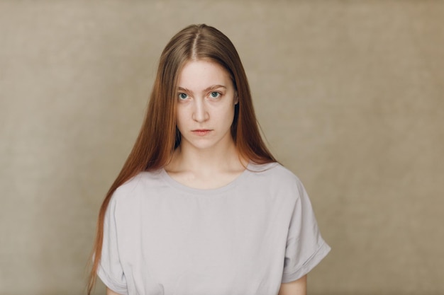 Portrait of young caucasian woman looking at camera against beige background