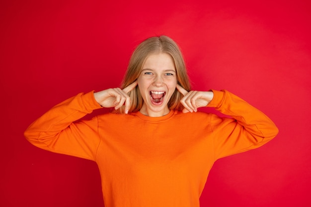 Photo portrait of young caucasian woman with bright emotions isolated on red studio background