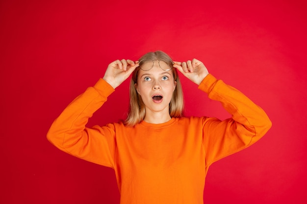 Portrait of young caucasian woman with bright emotions isolated on red studio background