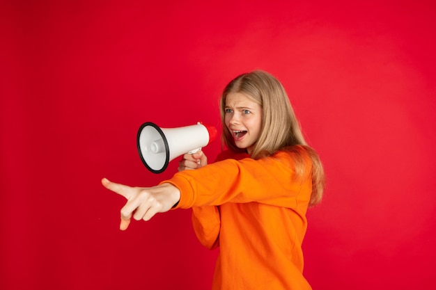 Portrait of young caucasian woman with bright emotions isolated on red studio background