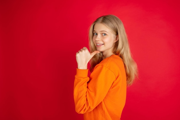 Portrait of young caucasian woman with bright emotions isolated on red studio background