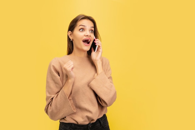 Portrait of young caucasian woman with bright emotions isolated on yellow studio background