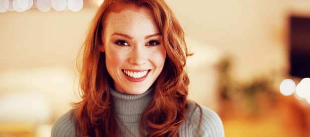 Portrait of a young caucasian woman with long brown hair\
looking to camera smiling at home at night with string lights in\
the background