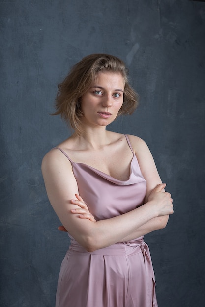 Foto ritratto di giovane donna caucasica con i capelli corti in posa in abito rosa, in piedi. bella ragazza in camicetta