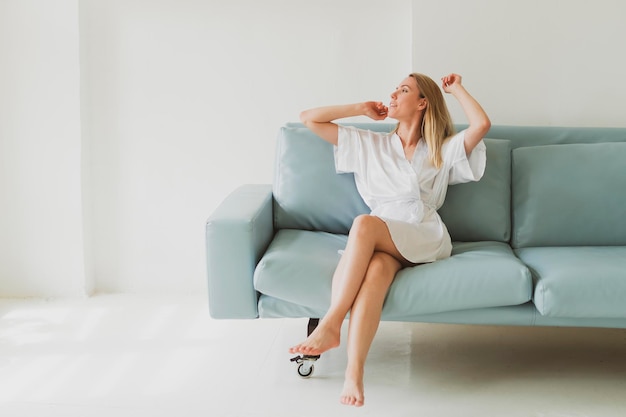 Portrait of a young charming woman in a silk robe at home on the sofa