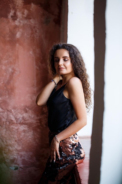 Photo portrait of a young charming woman with curly hair fairskinned girl in a black top and with a smile on her face curly woman in light clothes