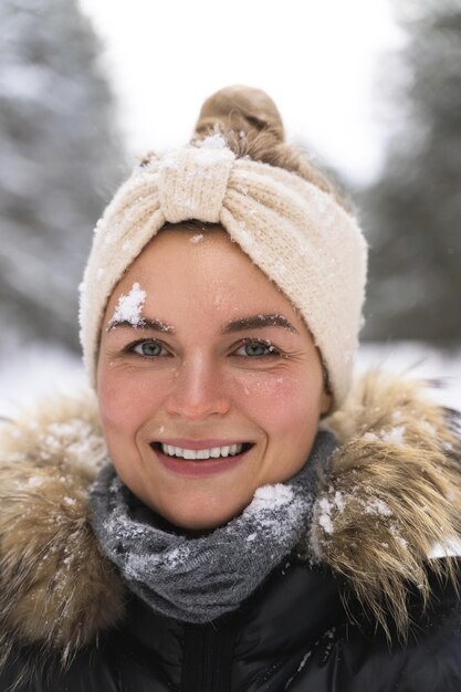 Portrait of young cheerful girl enjoying snowfall during beautiful winter day