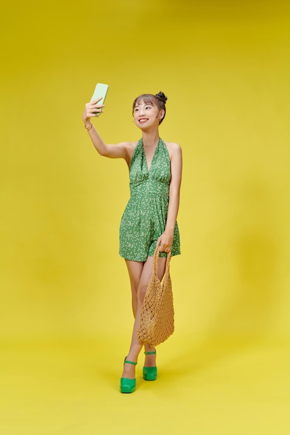 夏服の若い陽気な女性の肖像画は、スマート フォンで selfie を作る