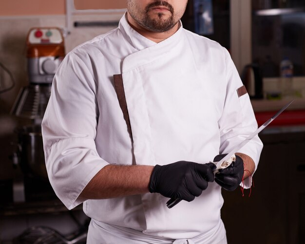 Портрет молодого шеф-повара чистит нож