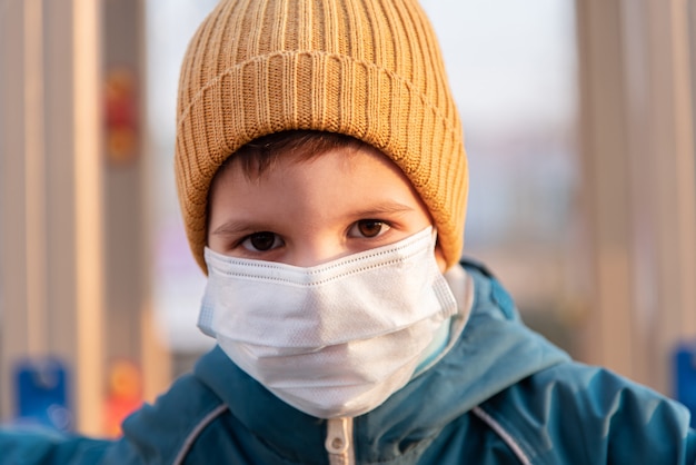 Portrait of a young child in a medical mask on the street during the coronavirus and Covid pandemic - 19