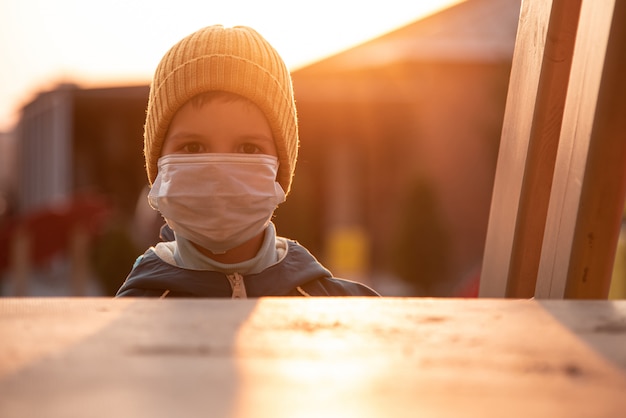 Foto ritratto di un bambino in una maschera medica sulla strada durante il coronavirus e la pandemia di covid - 19