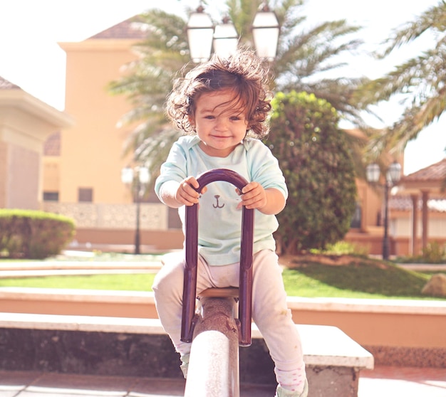 portrait of young child sitting on a seesaw