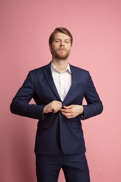 Portrait of young confident caucasian man isolated on coral background. Valentine's day celebration. Concept of human emotions, facial expression, love, relations, romantic holidays. Copyspace.