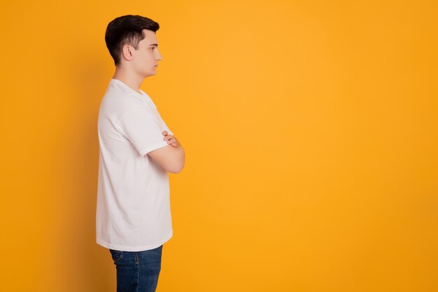 Portrait of young confident guy cross hands look empty space isolated over yellow background