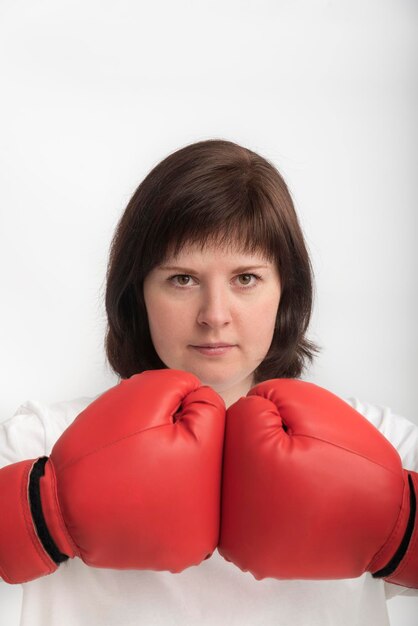 Portrait of young confident woman in boxing gloves on white background. Concept of feminism and the struggle for womens rights.