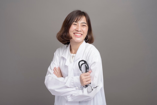 A portrait of young confident woman doctor isolated over grey background studio