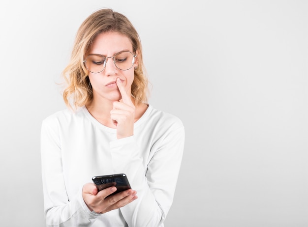 Portrait of a young confused girl in white short holding mobile