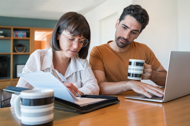 Portrait of young couple calculating and paying bills on laptop from home