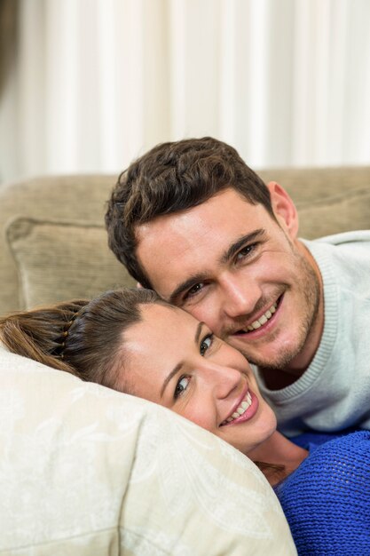 Portrait of young couple cuddling on sofa in living room