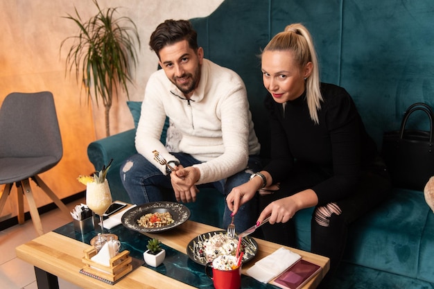 Portrait of Young Couple Eating Pancakes in Restaurant and Drinking Cocktail Chill and Colada