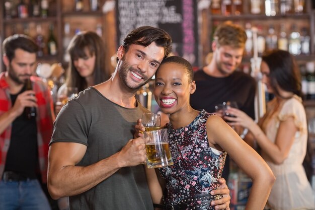 Photo portrait of young couple embracing while holding beer mugs