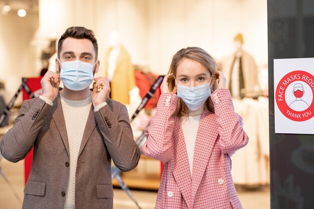 Foto ritratto di giovane coppia che guarda la telecamera mentre indossa le maschere durante la pandemia