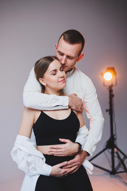 Portrait of a young couple in love in casual clothes hugging on a white background A happy married couple looks lovingly into each other's eyes