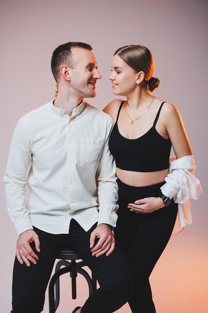 Portrait of a young couple in love in casual clothes hugging on a white background A happy married couple looks lovingly into each other's eyes