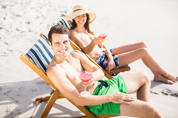 Portrait of young couple sitting on armchair with cocktail drink