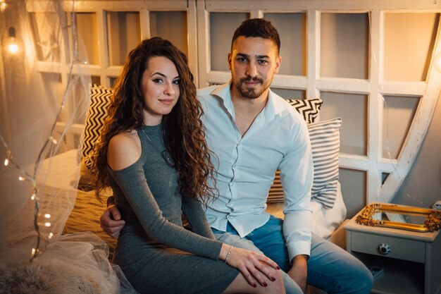 Photo portrait of young couple sitting on bed at home