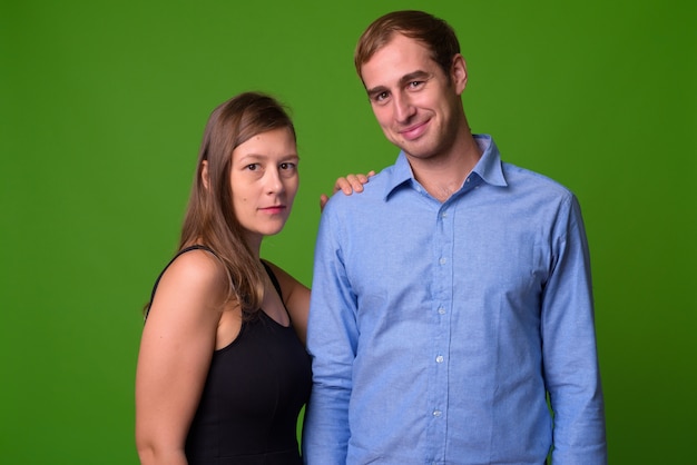 Portrait of young couple together against green wall