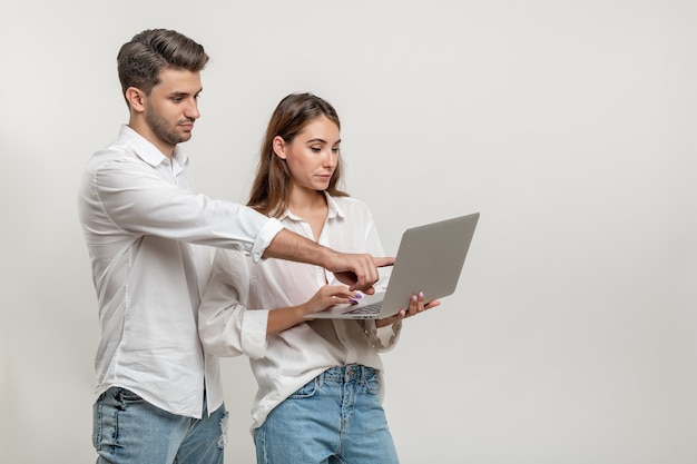 Photo portrait of young couple using laptop pointing on the screen isolated on white background