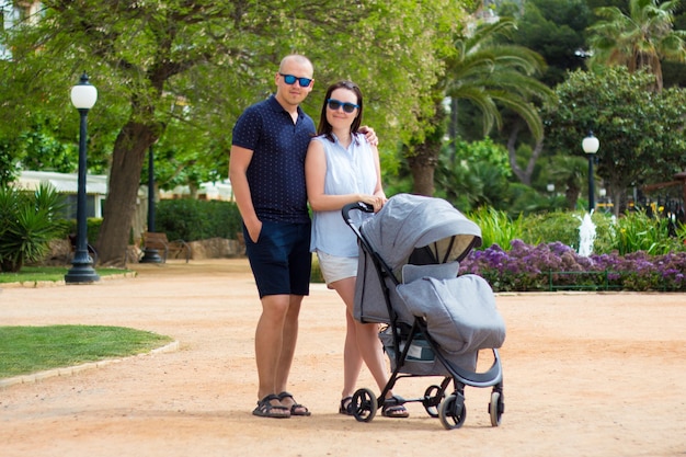 Portrait of young couple walking with modern baby stroller