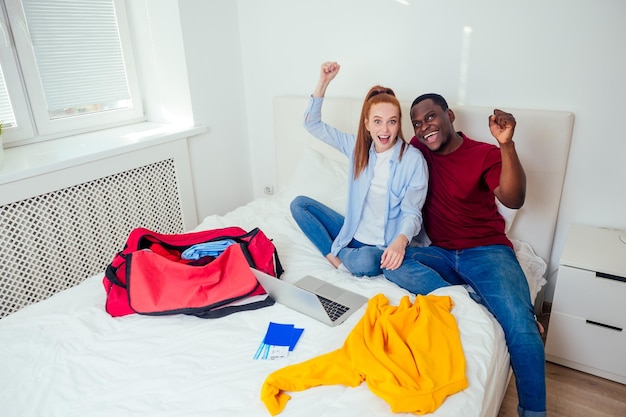 Portrait of young couple with passports luggage and tickets packaging clothes.