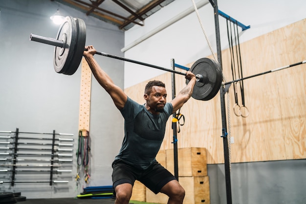 Ritratto di giovane atleta crossfit facendo esercizio con un bilanciere