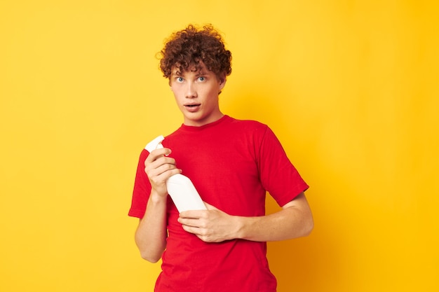 Portrait of a young curly man detergents home care posing yellow background unaltered